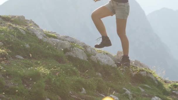 スローモーション クローズ アップ 勇気ある女性ハイカー山頂登山道オフ危険な大まかなロッキーマウンテンの棚の上に歩いて 急な壁の高いヨーロッパ アルプス日光浴の美しいビューを開く — ストック動画