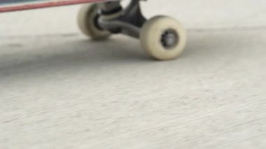 Ağır çekim yakın makro çekim: tanınmayan kaykaycı beton bir güneşli yaz gününde sokak boyunca kaykay. Bir kaykay güverte ve bir kaldırımda iplik tekerlekleri aşırı closeup