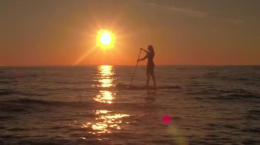 Hava, yakın: şişme paddleboard, sürme güzel kız binici deniz ve maceralı tatil sihirli altın günbatımında zevk yukarıda uçan. Deniz yüzeyi dalgalanan yansıtan güneş