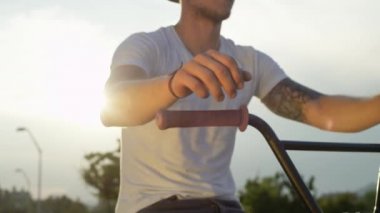 Ağır çekim Dof aşırı yakından: Bmx bisiklet ekipman ayrıntılarını, yaz aylarında gidon üzerinde eller yerleştirerek motorcu kulpları. Bisiklet gidon, holding bmx motorcu şehirde binmek için hazırlık arkasında parlayan güneş