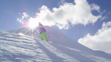 Ağır çekim yakın çekim: güneşli dağ backcountry güneşte üzerinden kar püskürtme el sürükle, toz ve iş sürme Extreme snowboard. Eğleniyor snowboard bakırlı taze kar snowboard