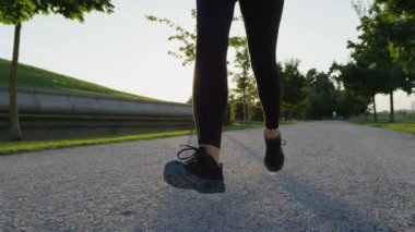 Ağır çekim Dof yakından: Enerjik genç kadın ağaçları arasında kumlu patika üzerinde çalışan ve yerel Parkta koşmaya zevk iyi durumda. Ağaç sağlayan canlandırıcı gölge sıcak yaz akşamı Kanopiler