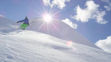 Ağır çekim yakın çekim: güneşli dağ backcountry güneşte üzerinden kar püskürtme el sürükle, toz ve iş sürme Extreme snowboard. Eğleniyor snowboard bakırlı taze kar snowboard