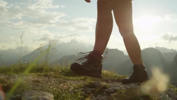 スローモーション クローズ アップ 勇気ある女性ハイカー登山山頂 危険な大まかな岩の多い山の尾根トレイルを歩きます 急な壁の高いヨーロッパ アルプス日光浴の美しいビューを開く — ストック動画