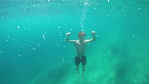 SLOW MOTION, CLOSE UP, UNDERWATER: Young man drowning in deep ocean, sinking to the rocky ocean bottom. Air bubbles leaving victim's mouth. Unexperienced bad swimmer facing terrible and painful death — Stock Footage Slow Motion Close Underwater Young Man Drowning Deep Ocean Sinking Royalty Free Stock Video