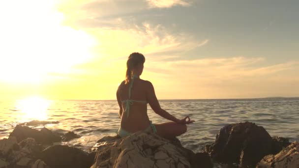 Close Up: Dívka sedící na skále vlnící se moře, meditoval v lotus jóga představuje, soustředit se v tichosti, pozorování dechu, relaxace těla a duše. Klid žena se snaží dosáhnout harmonie Zen