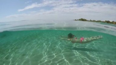 Ağır çekim, Close Up, sualtı: berrak okyanus gölünde sualtı dalış çekici genç esmer kız. Delici su yüzey ve çarpıcı beyaz kumlu deniz altındaki yansıtan güneş ışınları