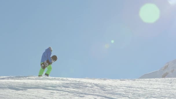 スローモーションをクローズ アップ 極端なスノーボーダーの冬で山の頂上に向かって新雪パウダーで上り坂のハイキングします バックカントリー マウンテン スキー リゾートの山頂に登るフリーライド スノーボーダー — ストック動画