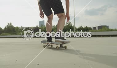 Ağır çekim yakın çekim: kaykay ve ollie hileler Caddesi üzerinde atlama tanınmaz kaykaycı. Kaykaycı'nın bacakları ve atlama spor ayakkabı aşırı closeup açık havada kaykay ile hüner çevirmek.