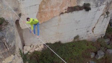 Hava, yakın: aşırı highliner terk edilmiş taş ocağı duvarlar arasında gerilmiş highline yürüyüş yukarıda uçan. Adam yavaşlama ve yaşam dolu slackline Kanyon Dengeleme emniyet kemeri ile