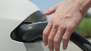 Kadar yakın, ağır çekim: şarj istasyonu üzerinden tanınmaz işadamı bitirdiğinden elektrikli araba. Lüks beyaz elektrik Tesla araba dolu. Ne zaman elektrik dolum rekabet kablo bağlantısını kesme