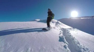 Yakın takip etmek: mutlu snowboard eğleniyor bir güneşli kış gününde snowboard backcountry karlı dağlarda. Taze kar kar bakırlı Dağı kayak merkezinde kapalı sürme aşırı freeride snowboarder