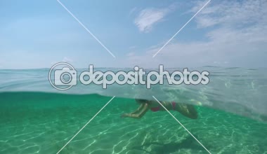 Ağır çekim, Close Up, sualtı: Gülümseyen genç kız resim mükemmel turkuaz mavi lagün Okyanusu egzotik beyaz kumsalları ile güzel tropikal Adası'nda su yüzeyinin altında yüzmeye uygun