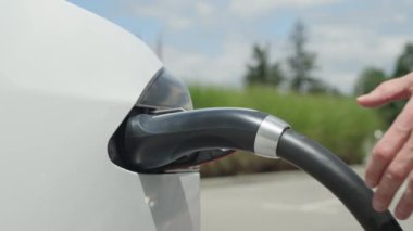 Kadar yakın, ağır çekim: şarj istasyonu üzerinden tanınmaz işadamı bitirdiğinden elektrikli araba. Lüks beyaz elektrik Tesla araba dolu. Ne zaman elektrik dolum rekabet kablo bağlantısını kesme