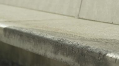 Ağır çekim Dof aşırı yakından: atlama ve sokakta beton bankta sürgülü tanınmaz kaykaycı. Patencinin kaykay bacaklar ve hile bir şehirde kaykay ile taşlama iş closeup