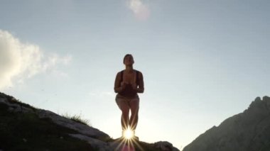 Ağır çekim, Close Up, düşük açı: dağ tepe üzerinde büyük kayanın üzerinde duran, elleri kadar yükselterek, atlama ve bacaklar şaşırtıcı güneşli akşamı outstretching neşeli genç kadın. Mutlu kız zevk başarı