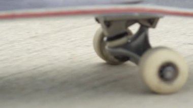 Ağır çekim yakın makro çekim: tanınmayan kaykaycı beton bir güneşli yaz gününde sokak boyunca kaykay. Bir kaykay güverte ve bir kaldırımda iplik tekerlekleri aşırı closeup