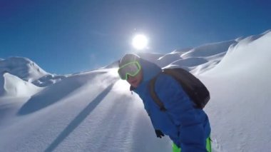 Neşeli snowboardcular güneşli kış günlerinde karlı dağlarda snowboard yaparken eğleniyorlar. Aşırı serbest gezen snowboardcular taze toz kar sürüyor ve piste toz yapıyor.