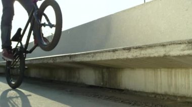 Ağır çekim Dof yakından: Park beton bir bankta atlama ve kenar güneşli günde sürgülü aşırı bmx motorcu. Havalı motorcu parlayan güneş atlama ve peg yapmak hileci yaz aylarında eziyet