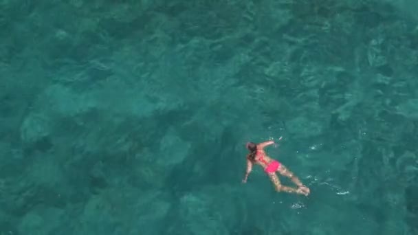 迷人的年轻白种女人游泳在深美丽的绿松石海洋 阳光穿透波光粼粼的透明水揭示惊人的岩石和沙海底部 — 图库视频影像
