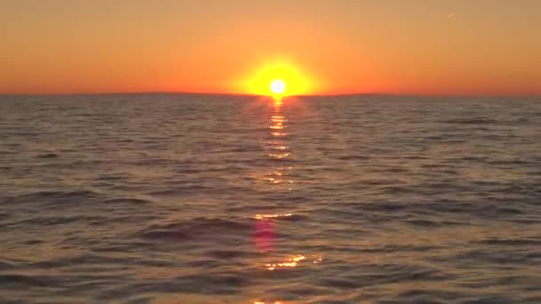 航空写真 美しい黄金色とオレンジ色の夕日静かな夏の夜に静かな海の表面の上飛んでいます クロアチアで見事な野生のビーチで光沢のある波打つ海の上を反映して素晴らしい桃空 — ストック動画