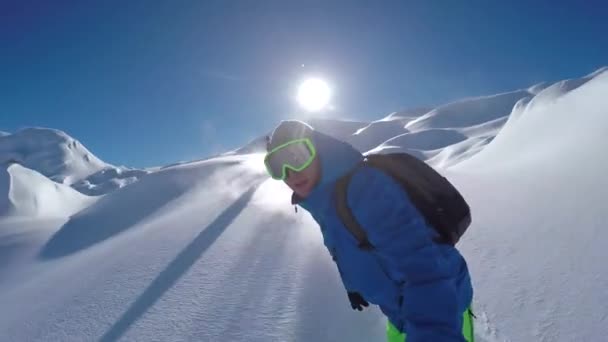 セルフィー 陽気なスノーボーダーは 雪の山の中で晴れた冬の日にスノーボードのバックカントリーを楽しんでいます 新雪に乗ってパウダーを行う極端なフリーライドスノーボーダーは スキー場をオフにします — ストック動画