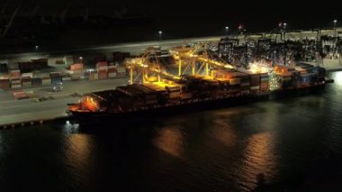 Hava yakın: çelik vinç ağır yük nakliye konteyner sevk irsaliyesinde büyük yükleme demirlemiş Liman kargo gemisiyle. Taşıma, lojistik, Ticaret Merkezi rafineri Harbor ile gece yaktı