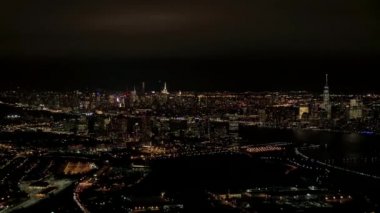Hava Heli Shot: New Jersey liman sanayi bölgesi içinde yukarıda geceleri uçan, bakan ikonik Nyc şehir manzarası ile parlak gökdelenler ile Brooklyn ve Queens cityscape arka planda yaktı