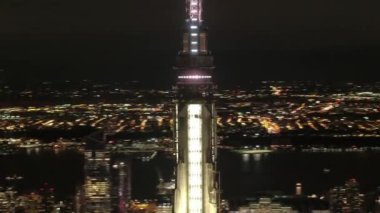Hava Heli Shot, Close Up: dünyaca ünlü Empire State binasının tepesinde karanlık anten içinde parlayan etrafında uçan. Brooklyn borough ile New York'ta büyülü ışık yaz gecesi alev aldı.