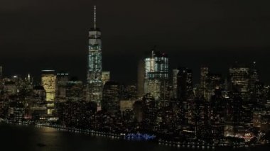 Hava Heli Shot: Skyline görünümü New York Yarımadası ikonik Downtown Manhattan mali ile bölgesinin ünlü büyük waterfront gökdelenler ve dev ofis binaları geceleri parlayan ışıkları ile alev aldı.