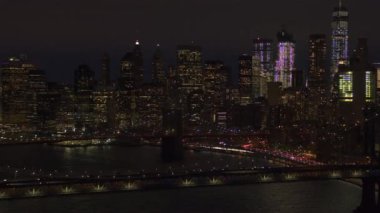 Ünlü Manhattan Köprüsü ve ikonik Brooklyn Köprüsü Downtown Manhattan'a önde gelen doğru hava Heli Shot: uçan finans bölgesine ışıkları ile gece aydınlandı. Araba sıkışan karayolu üzerinde commuting