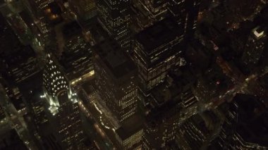 Hava Heli Shot Clsoe Up: Midtown Manhattan sokaklarında gece kuşbakışı bakış açısıyla tarafından aydınlatılmış. Karanlık yükseliyor ofis binaları yukarıda parlayan ışıkları ile ikonik Chrysler Binası alev aldı.