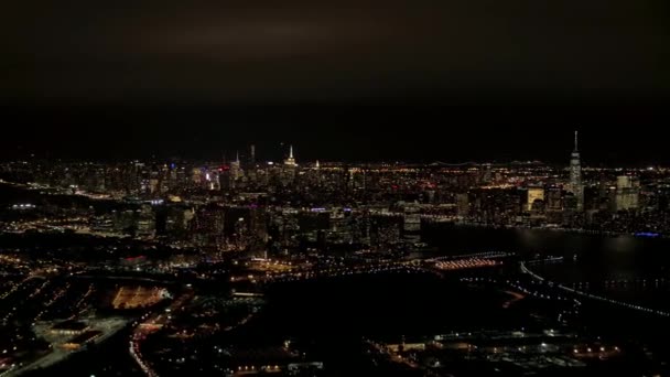 ヘリは夜間飛行工業地帯のニュージャージー港の上と象徴的な Nyc ダウンタウンのスカイラインを見渡す明るい高層ビルとブルックリンやクイーンズ街並みバック グラウンドで — ストック動画