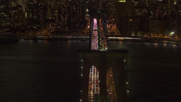 なし表示商標自動車交通が象徴的なブルックリン橋を渡って動く撮ヘリ ライトアップ灯不思議な夏の夜にニューヨーク市で 通勤ラッシュの時間に仕事からの人々 — ストック動画