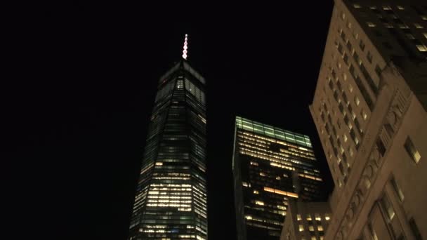 クローズ アップ 低視野角 関連メインの建物で窓が照らされた複雑な再建の世界貿易センターの夜 ロウアー マンハッタンのダウンタウンのビジネス地区 ニューヨークのフリーダム タワーは有名な — ストック動画