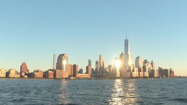 エスタブリッシング ショット 象徴的なダウンタウン マンハッタン ニューヨーク市のスカイラインの夕日の黄金の輝き モダンなガラスの高層ビルと澄んだ青い空を背景に照らされたウォーター フロント高級住宅 — ストック動画