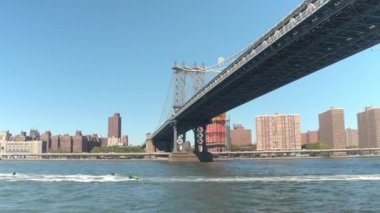 Düşük görüş açısı kadar yakın: Mutlu çiftler ve jet-Doğu Nehri boyunca meşgul karayolu ikonik Manhattan Köprüsü altında güneşli yaz günü New York'ta Kayak arkadaşlar Downtown Manhattan bakan