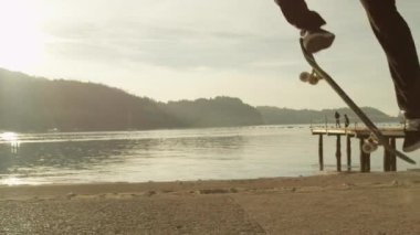 Ağır çekim yakın çekim: kaykay ve yüksek altın batan güneşin karşı okyanus kıyısında Promenade merdivenlerden atlama Pro kaykaycı. Gün batımında Ollie kaykay hile yaparak patenci