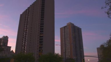Düşük görüş açısı, Close Up: Uzun boylu highrise konut binalar ve gökdelenler pembe-mavi gökyüzü şafakta karşı. New York şehir merkezinde çağdaş kule blok daire geçmiş güneş doğarken sürüş