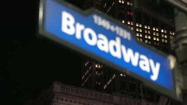 Close Up, Dof: Ünlü mavi renkli Broadway trafik tabelası gece sokak köşesinde. Arka planda New York, Manhattan şehir iş bölgesinde yanan pencereler ile Yüksek ofis binası