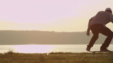 Ağır çekim, Close Up: kaykay ve altın ışık günbatımı okyanus boyunca 360 flip hüner atlama kaykaycı kontrast. Deniz güneş doğarken, kaykay sürme kaykaycı