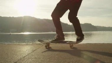 Ağır çekim, Close Up: kaykay ve altın ışık güneş doğarken okyanus boyunca 360 flip hüner atlama tanınmaz kaykaycı. Kumsalda güneş doğarken kaykay sürme kaykaycı