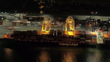 Hava yakın: çelik vinç ağır yük nakliye konteyner sevk irsaliyesinde büyük yükleme demirlemiş Liman kargo gemisiyle. Taşıma, lojistik, Ticaret Merkezi rafineri Harbor ile gece yaktı