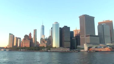 Staten Adası feribot terminal Aşağı Manhattan iş bölgesinde toplu taşıma tekne demirlemiş. New York şehir manzarası ile çağdaş gökdelenler ve ofis binaları Altın ışık batımında