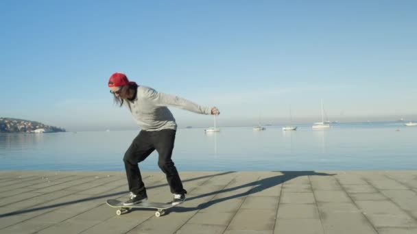 閉じるをスローモーション Dof 認識できないスケート ボード スケート ボード 晴れた日に海岸沿いの遊歩道にオリーのフリップ トリックをジャンプします ビーチでキックフ リップ — ストック動画