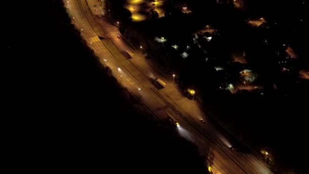 空中直升机射击 在繁忙的交通高速公路上飞行 夜间点燃了汽车灯 汽车旅行 半卡车运输 通勤者沿高速公路通过郊区村庄 — 图库视频影像