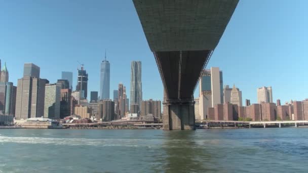 低角度のビュー クローズ アップ 驚くべき過去の象徴的なブルックリン橋と小さなドイツ近所のアパートへ有名なニューヨークの摩天楼旅行東川の観光船クルーズ — ストック動画