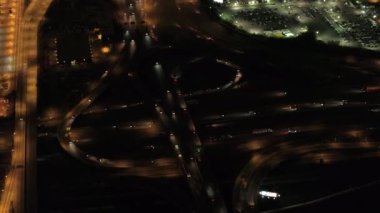 Hava Heli Shot: ışıklar devasa çoklu seviye değişimi yol kavşağı on-rampalar ve rampaları kapalı ile karayolu üzerinde ile aydınlandı yukarıda uçan. Ticari bölgesinde, gece seyahat araçlar yoğun trafik