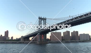 Düşük görüş açısı, Close Up: Gezi ünlü New York şehir manzarası Doğu Nehri üzerinde cruise. Gökdelenler, ofis binaları ve lüks waterfront condominiums boyunca gündoğumu ikonik Manhattan Köprüsü