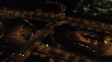 Hava Heli Shot: ışıklar devasa çoklu seviye değişimi yol kavşağı on-rampalar ve rampaları kapalı ile karayolu üzerinde ile aydınlandı yukarıda uçan. Ticari bölgesinde, gece seyahat araçlar yoğun trafik